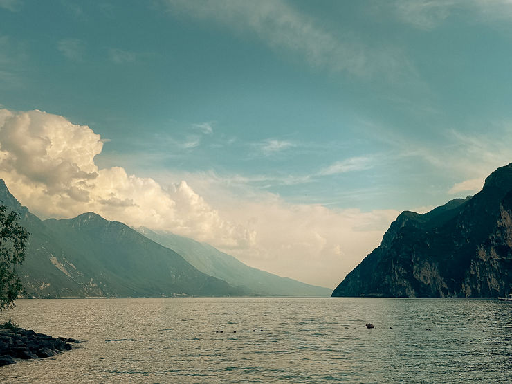Berglandschaft mit See im Vordergrund und bewölktem Himmel