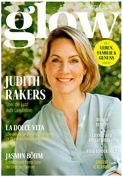 Porträt von Judith Rakers mit schulterlangem, gewelltem Haar und hellblauem Hemd vor unscharf grünem Hintergrund auf dem Cover der Zeitschrift "glow".