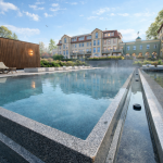 Naturstein-Außenpool des Naturresorts & Spa Schindelbruch im Südharz mit dampfendem Wasser und Blick auf das Hotelgebäude
