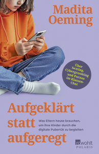 Kind sitzt mit verschränkten Beinen in Jeans und orangefarbener Kapuzenjacke und hält ein Smartphone in den Händen