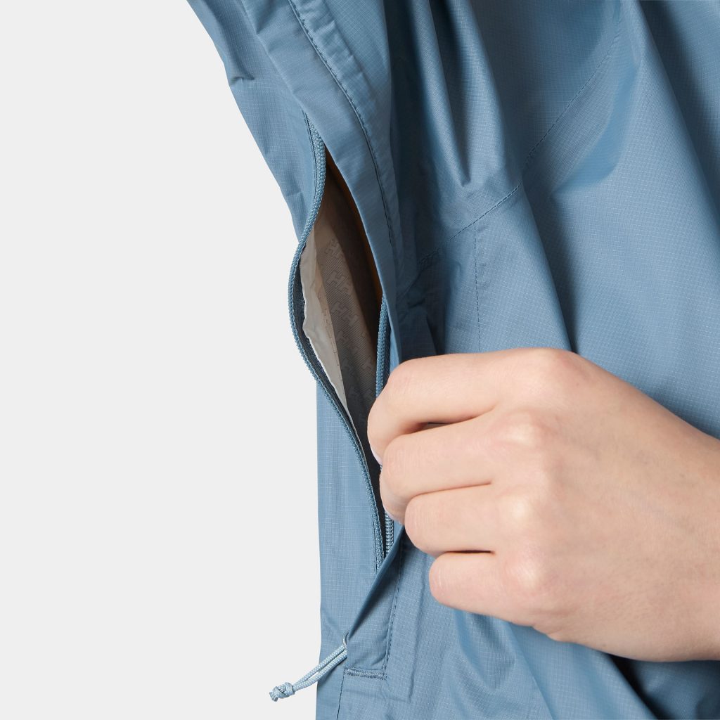 Hand öffnet Reißverschluss einer blauen Jacke an der Seite