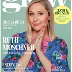 Ruth Moschner mit blonden Haaren in blauem Kleid mit pinken Blumen vor grünem Hintergrund mit Magazinüberschriften