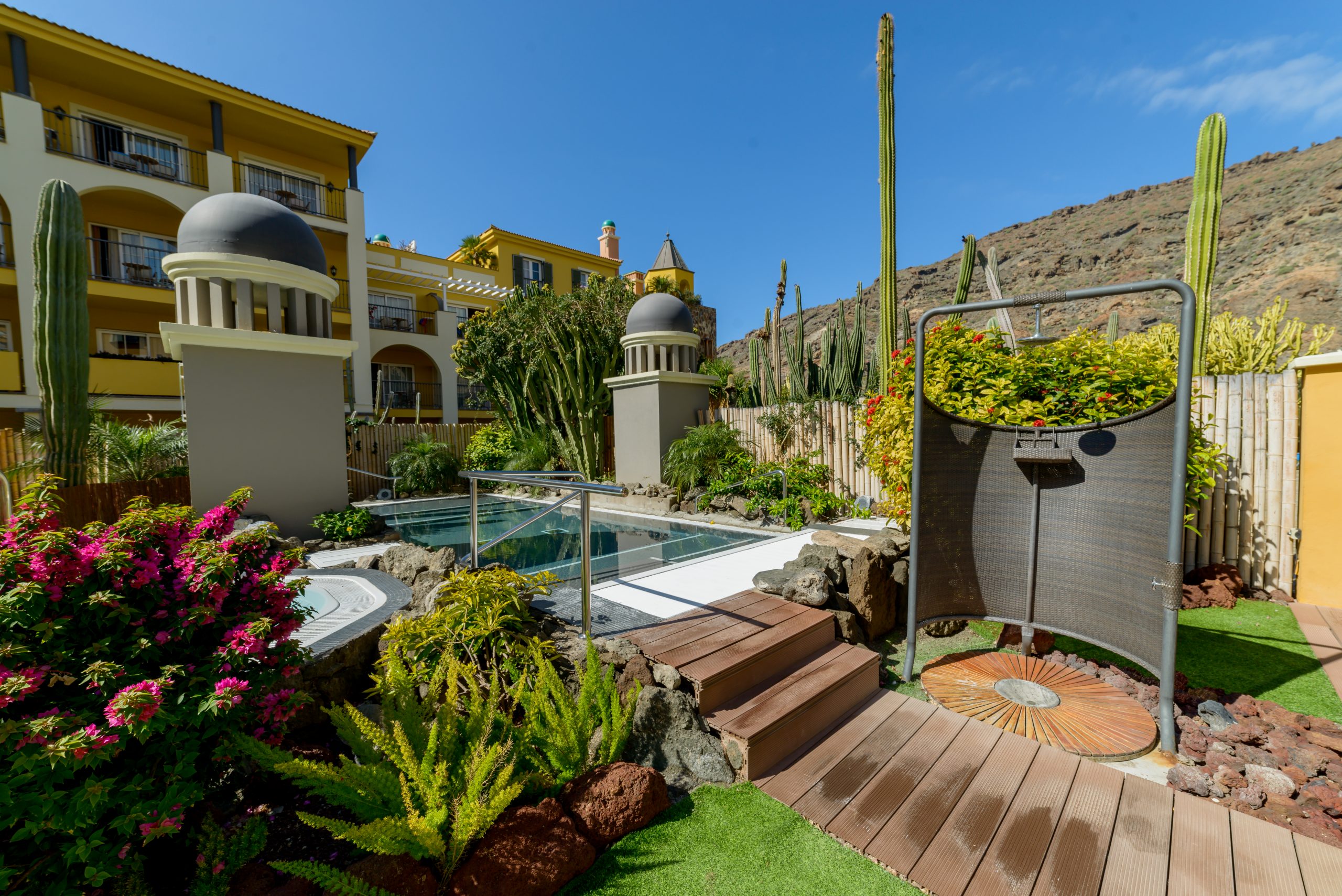 Hotelgarten mit Pool und Kakteen vor Bergkulisse