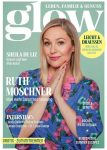 Ruth Moschner mit blonden Haaren trägt ein blaues Kleid mit pinken Blumen und hält die Hände vor der Brust gefaltet vor einem Magazin-Cover mit dem Titel 'glow'