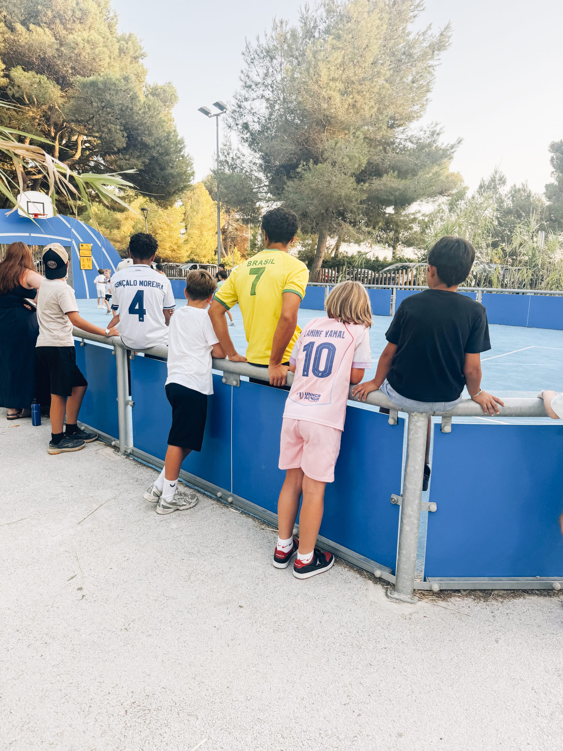 Kinder verfolgen das Fußballturnier am Zaun