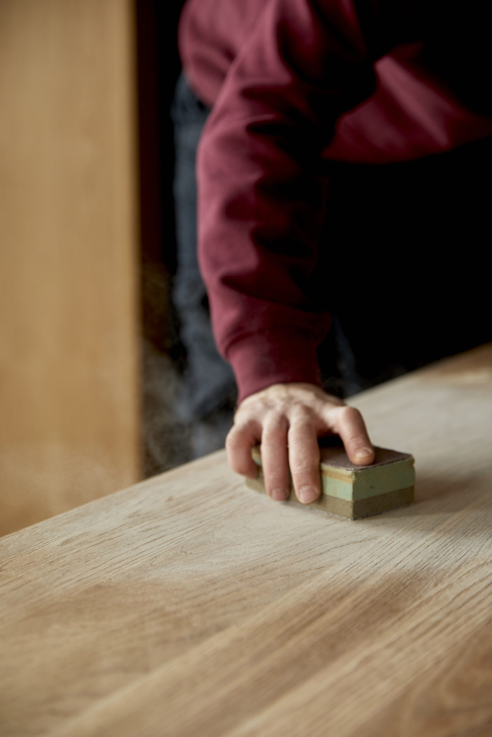 Handwerker schleift eine Holzplatte von Hand